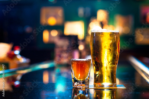 Pint of Beer and shot of Whiskey on bar at night with colorful lights