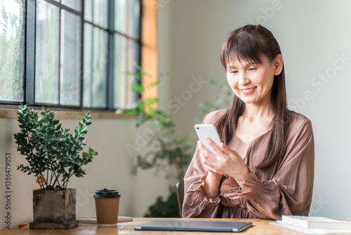 カフェでテレワーク・ノマドワークする中高年のアジア人女性
