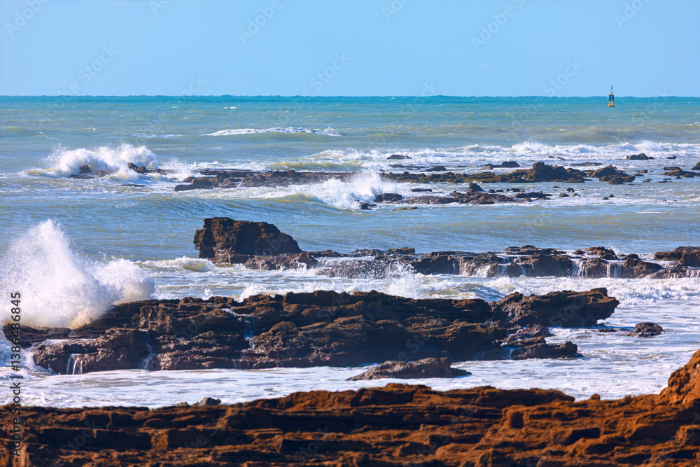 Powerful waves crash against jagged rocks, creating a dramatic coastal scene. vast expanse of ocean, dotted with dark rocks, stretches to the horizon