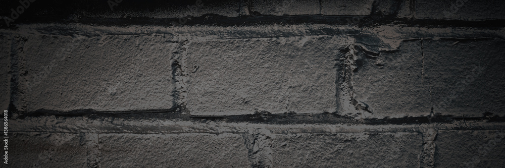 Old brick wall. The texture of weathered grungy brickwork. Panorama of a wall with a rough masonry surface. Dark wide panoramic background for design. Shaded vintage texture with dark vignette.