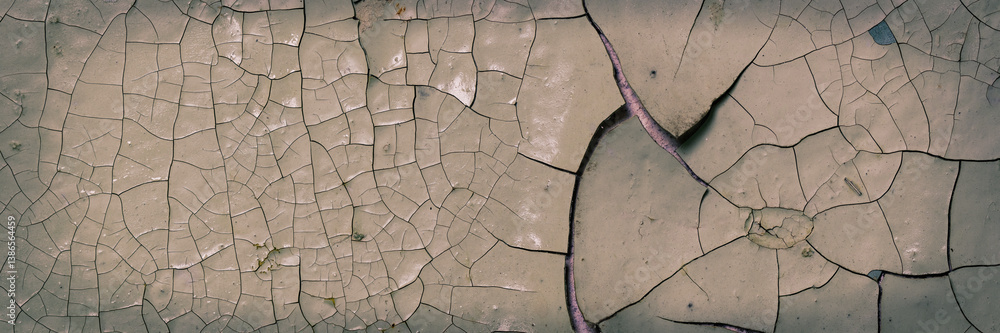Peeling paint on the wall. Panorama of a concrete wall with old cracked flaking paint. Weathered rough painted surface with patterns of cracks and peeling. Panoramic texture for background and design.