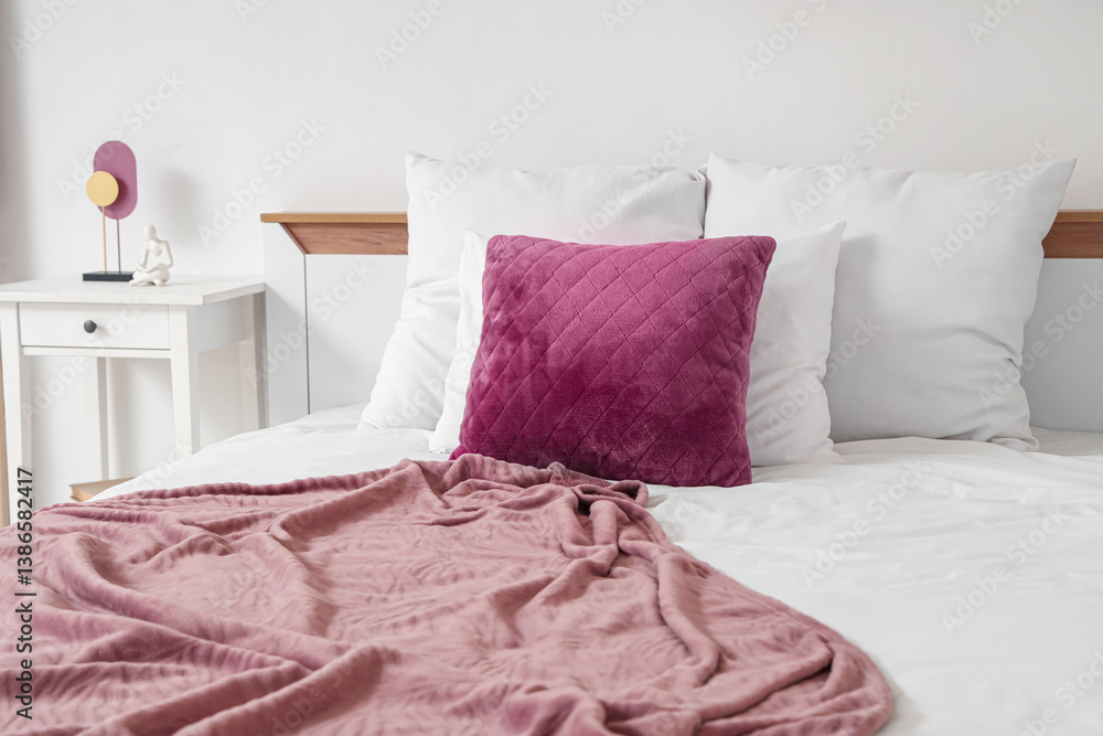 Obraz premium Cozy modern bedroom interior with pink blanket, white bedding, and decorative nightstand