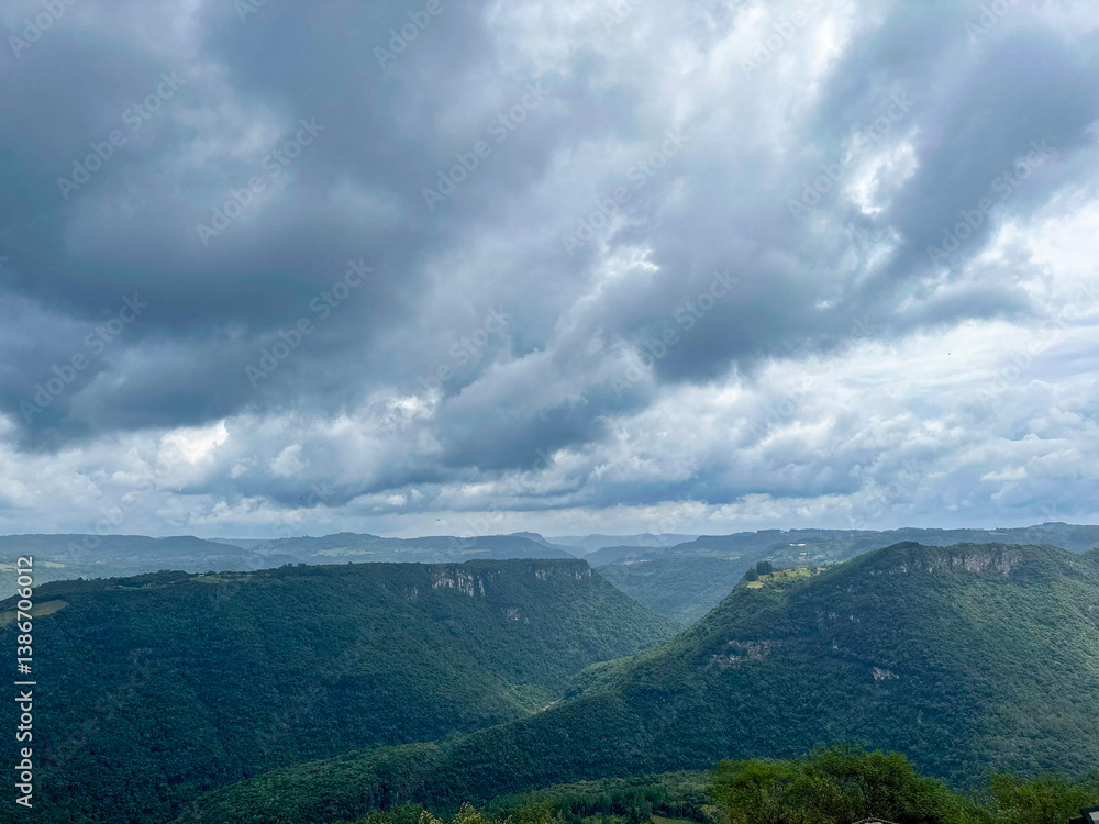 Obraz premium Scenic landscape of lush green mountains under a dramatic cloudy sky in southern Brazil, showcasing natural beauty and atmospheric weather