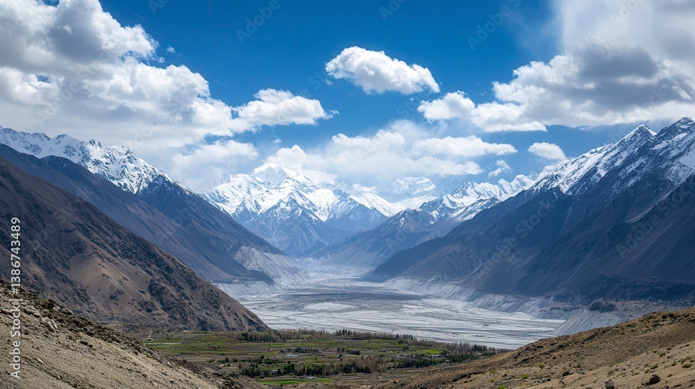 Panoramic view of a snow-capped mountain range valley with a small village. Panoramic view of a snow-capped mountain range valley with a small village.
