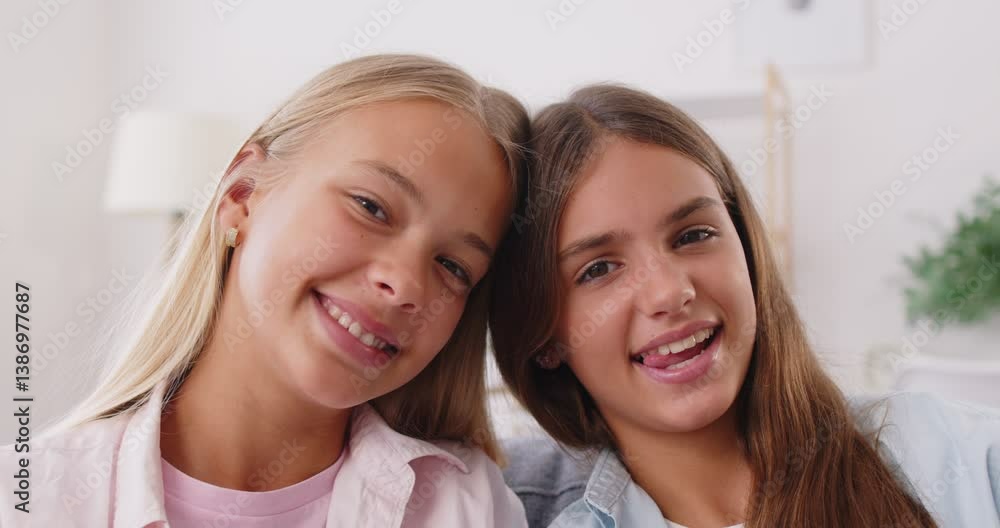 Portrait of happy smiling pretty children sisters sitting at home together. Teenage girls in casual clothes looking cheerful at camera indoors. Family and love concept. 4k video. Slow motion video. Portrait of happy smiling pretty children sisters sitting at home together. Teenage girls in casual clothes looking cheerful at camera indoors. Family and love concept. 4k video. Slow motion video.