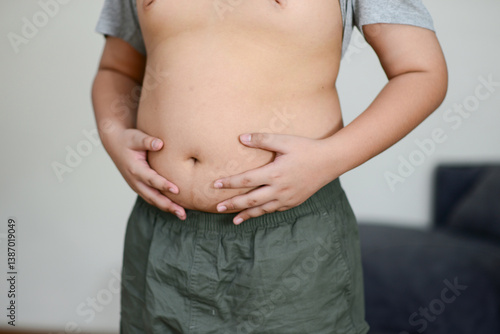 Obraz na płótnie A fat child with a fat belly holds his stomach with his hands. w salonie