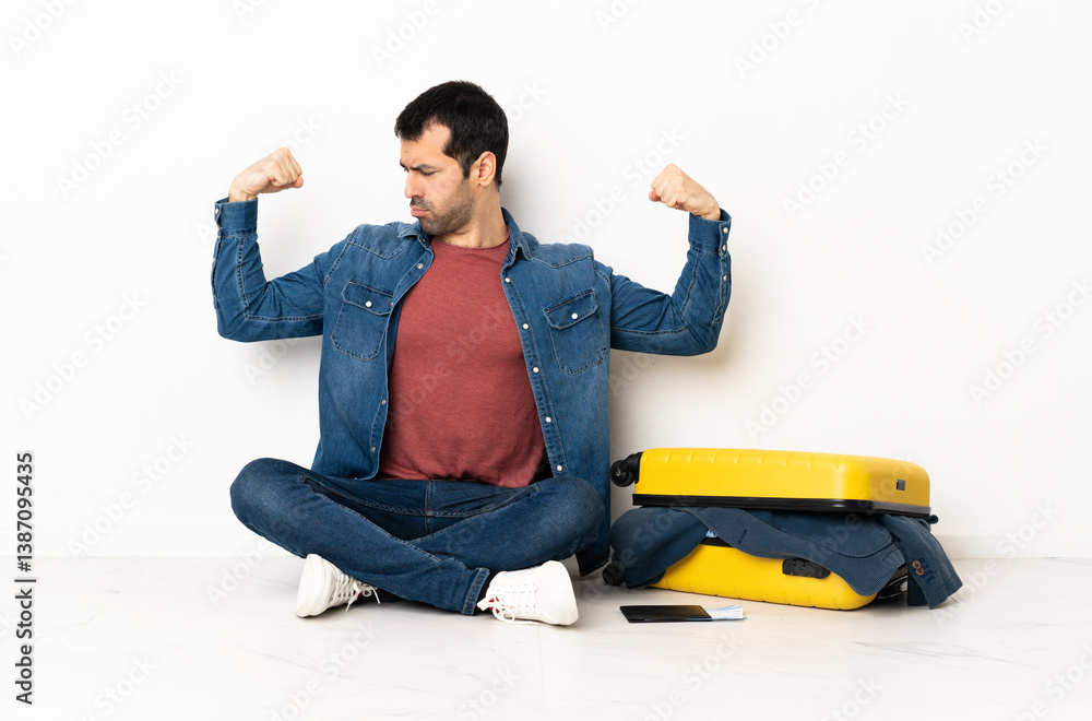 Caucasian handsome man with a suitcase full of clothes sitting on the floor at indoors doing strong gesture Caucasian handsome man with a suitcase full of clothes sitting on the floor at indoors doing strong gesture