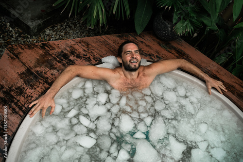 Quadro su tela Man takes an ice bath outdoors in a lush tropical setting