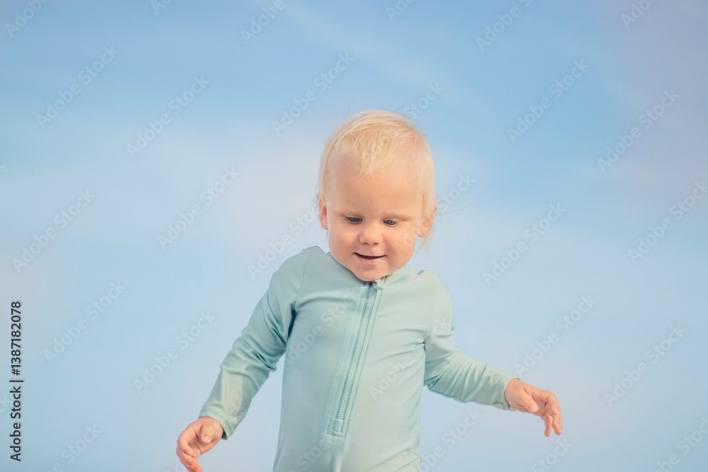 A joyful little toddler is happily enjoying a delightful playful moment under a bright clear blue sky