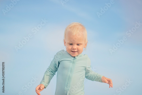 Obraz na płótnie A joyful little toddler is happily enjoying a delightful playful moment under a bright clear blue sky w salonie