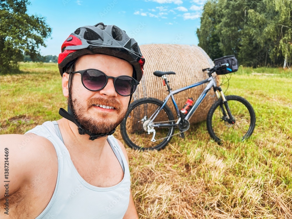 Man Takes Selfie with Bike in Field Surrounded by Haystacks