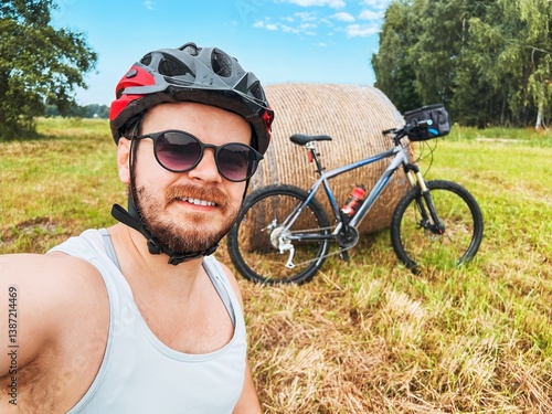 Man Takes Selfie with Bike in Field Surrounded by Haystacks