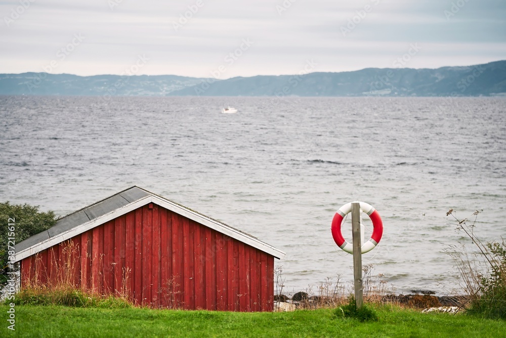 Red wooden cabin with foliage on roof by lake