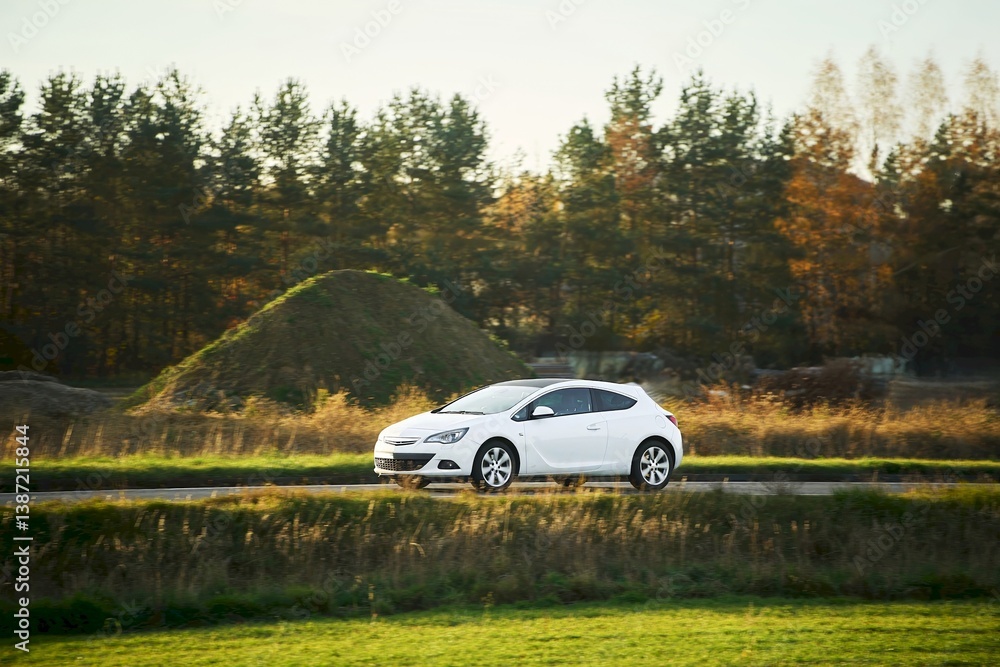 Hybrid hatchback vehicle near forest in autumn