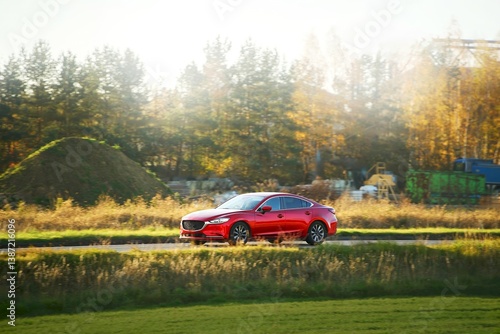Red sports sedan passing through nature