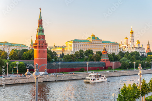 View of Kremlin with Vodovzvodnaya tower, Grand Kremlin Palace from repaired Bolshoy Kamenny Bridge in Moscow city on sunny summer day. Cruise ship sails on the Moscow river
