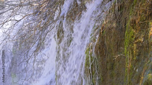 A river source cascades over rocks, creating  waterfall that sparkles in the sunlight