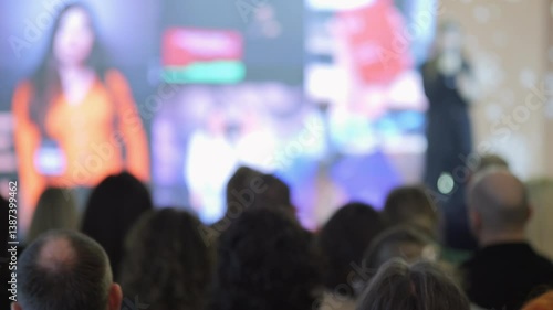 Wallpaper Mural Large crowd of people are watching a woman on a screen. The woman is wearing an orange shirt Torontodigital.ca