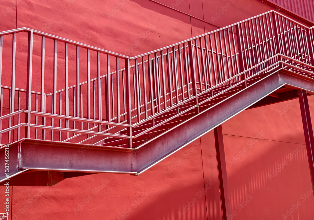 Fototapeta premium A set of stairs ascending a large red wall