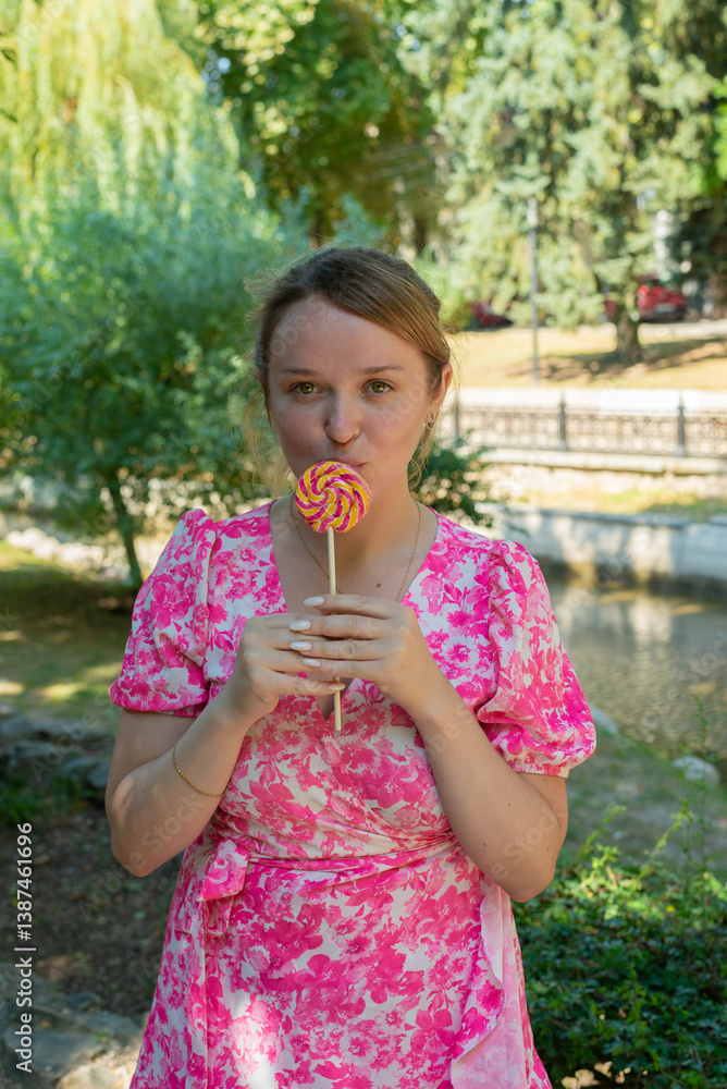 Fototapeta premium Pretty blonde girl wearing pink and white dress in the park 