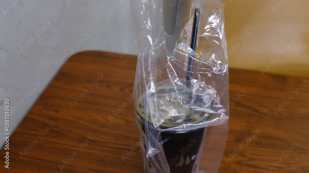 A plastic cup with a straw in it is sitting on a wooden table A plastic cup with a straw in it is sitting on a wooden table