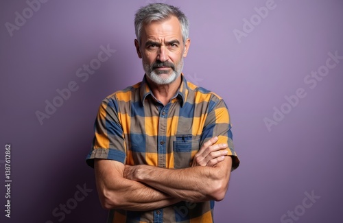 Serious elderly man with gray hair arms crossed. Attractive hoary person wears casual colorful shirt. Isolated purple background. Skeptic nervous disapproving expression.