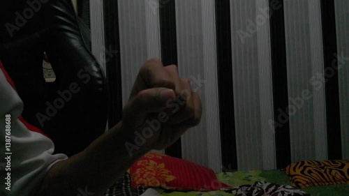 Close-up of a person's hand making a fist, seated in a room