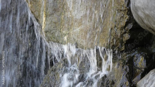 A waterfall is flowing down a rock. The water is white and clear. The rocks are grey and brown