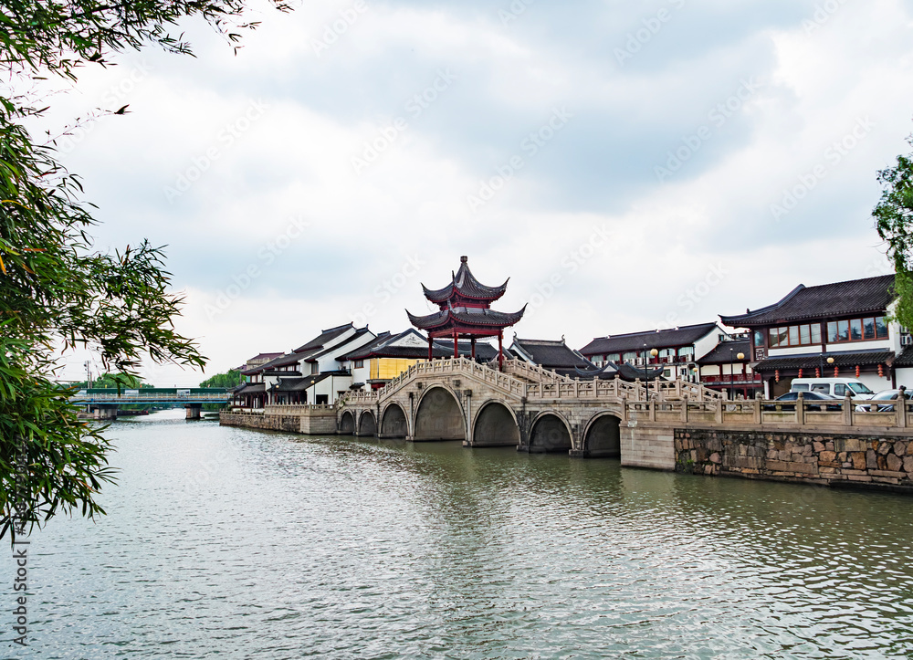 Fototapeta premium Scenic view of a traditional bridge and architecture alongside a tranquil river in a historic Chinese town