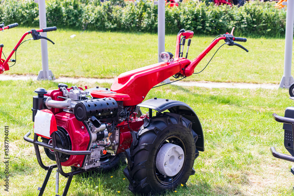 Red agricultural tiller displayed outdoors at a farming equipment expo in summer