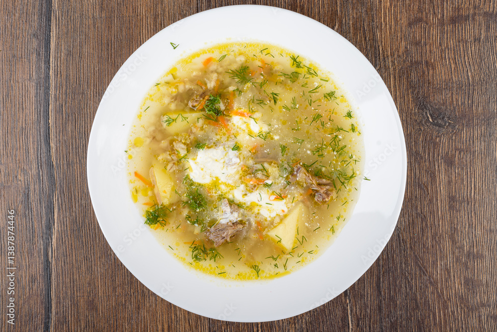 Top view of a plate of freshly prepared Leningradsky rassolnik soup with beef in a rich golden broth. Top view of a plate of freshly prepared Leningradsky rassolnik soup with beef in a rich golden broth.