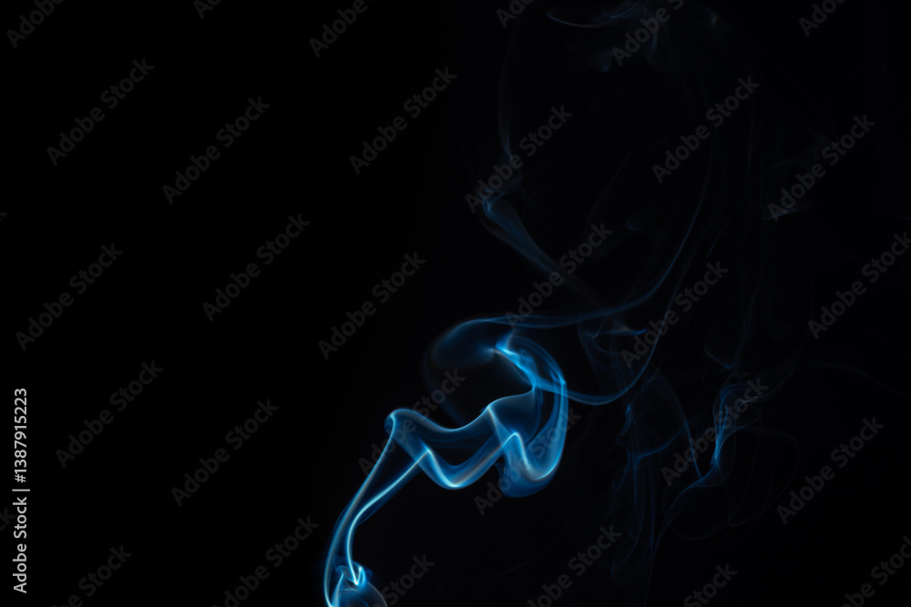 Obraz premium Wispy blue smoke wave flowing against a black background, creating a sense of mystery and elegance. Abstract and atmospheric concept. Swirling, writhing smoke to overlay on your photos