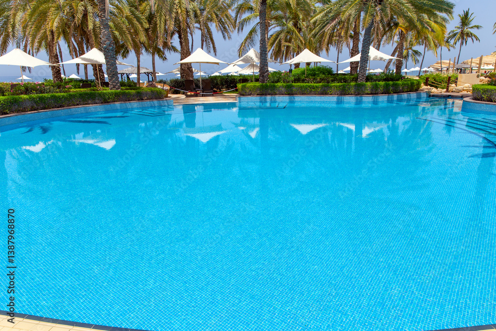 Swimming pool with clear water surrounded by palm trees in one of the best resorts Swimming pool with clear water surrounded by palm trees in one of the best resorts