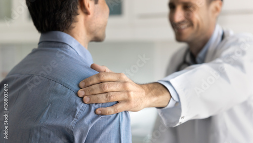 Cuadro en lienzo Smiling doctor in uniform speaking with male patient, touches his shoulder as ge