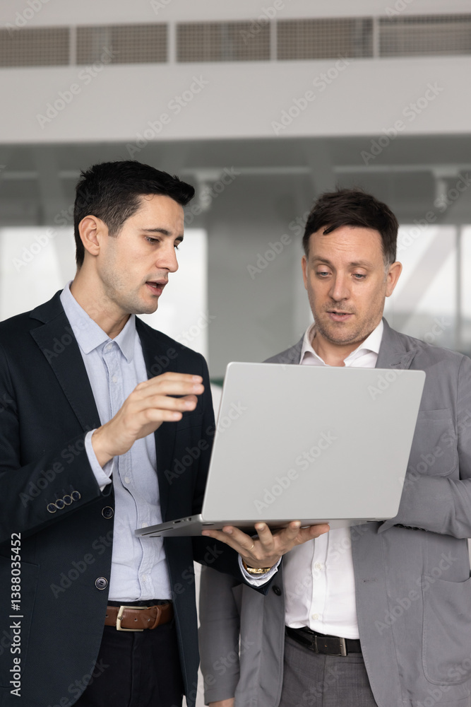 Diverse business colleagues discussing online project, using laptop for analyzing Internet statistic data. Manager asking colleague, expert for advice, showing electronic report on computer Diverse business colleagues discussing online project, using laptop for analyzing Internet statistic data. Manager asking colleague, expert for advice, showing electronic report on computer