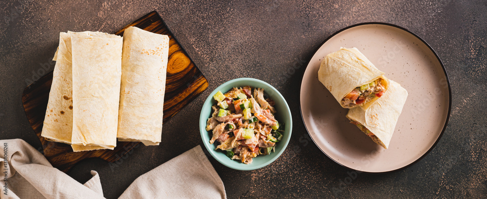 Shawarma in pita bread with meat and vegetables on a plate on the table top view web banner
