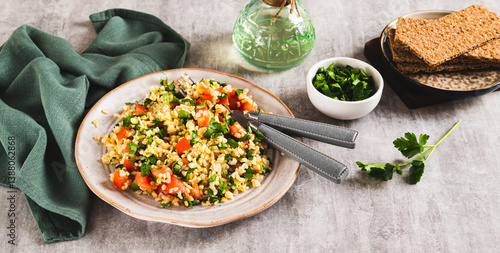 Tabbouleh salad with bulgur, tomato and parsley on a plate on the table web banner