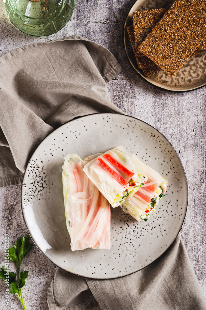 Spring rolls with crab meat, cucumber and herbs on a plate on the table top and vertical view