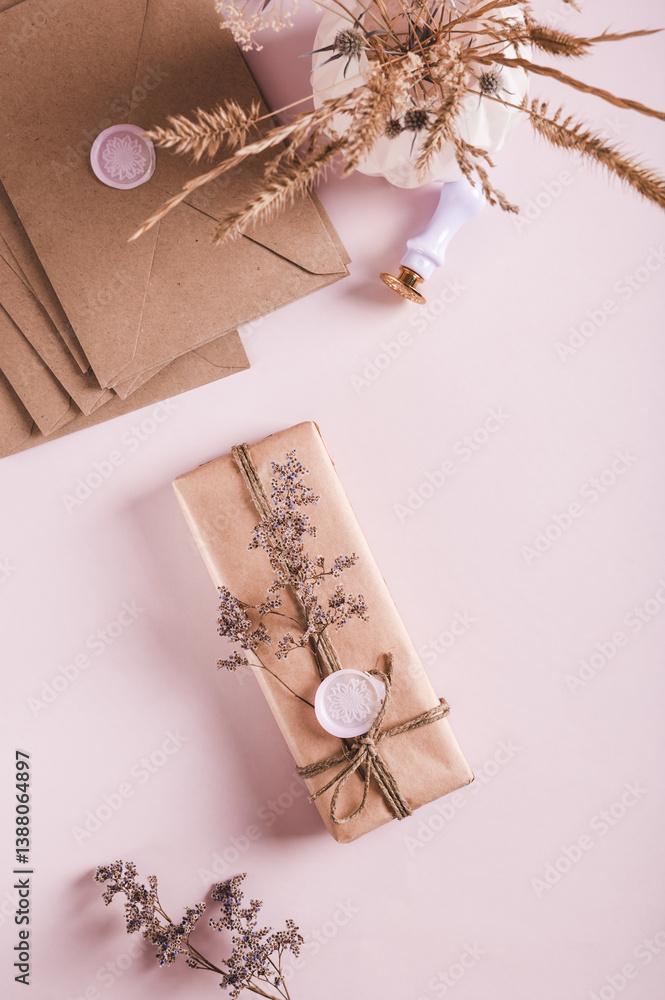 Gift in craft paper with wax seal and dried flowers on pink top and vertical view