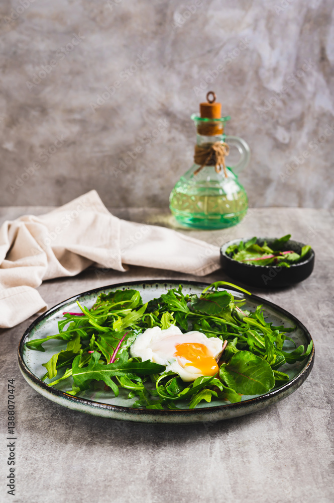 Poached egg in arugula and chard leaves on a plate on a table vertical view