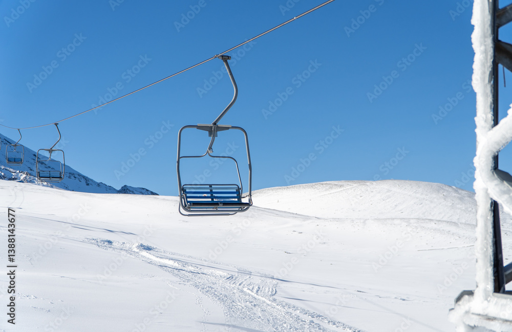 Empty chair lift moving in the clear skies during winter.