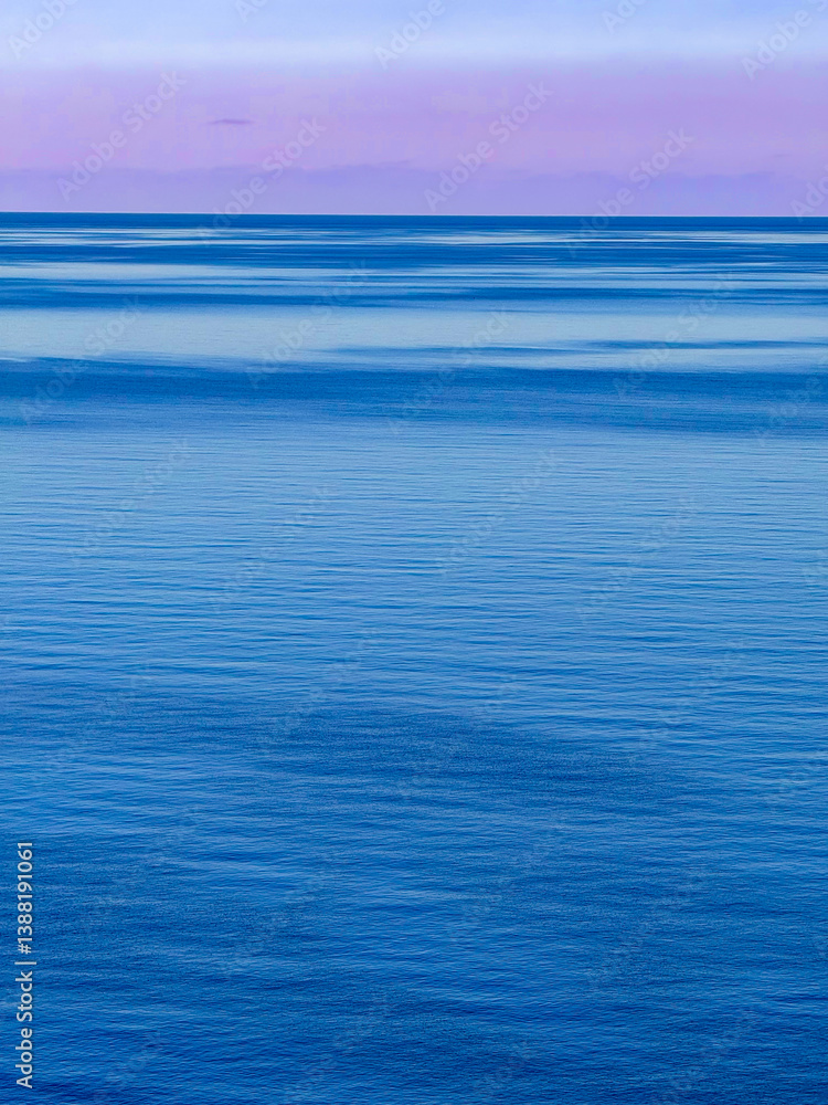 Fototapeta premium Minimalist morning landscape of the calm Aegean Sea under a clear sky. The smooth, deep blue water surface and soft gradients in gentle pastel colours evoke a sense of peacefulness and endless space.