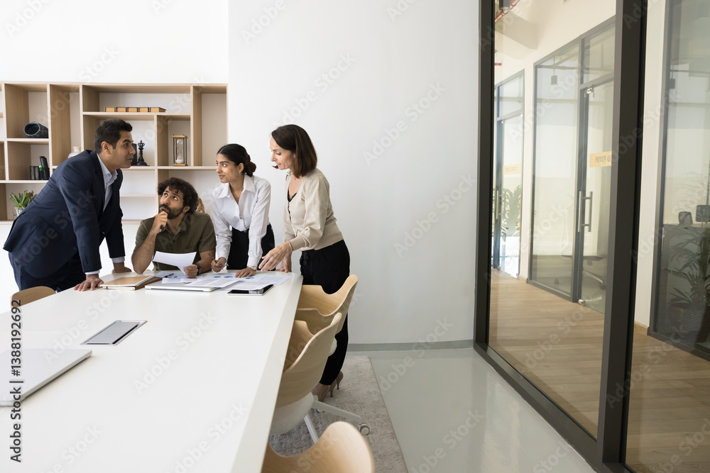 Four multi-national teammates solving business retailed matters, gathered in modern conference room for strategic decision-making, review financial report, forecasting and planning strategy. Teamwork Four multi-national teammates solving business retailed matters, gathered in modern conference room for strategic decision-making, review financial report, forecasting and planning strategy. Teamwork
