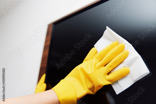 Obraz na płótnie Woman in yellow gloves cleaning black television screen with white and yellow cloth w salonie