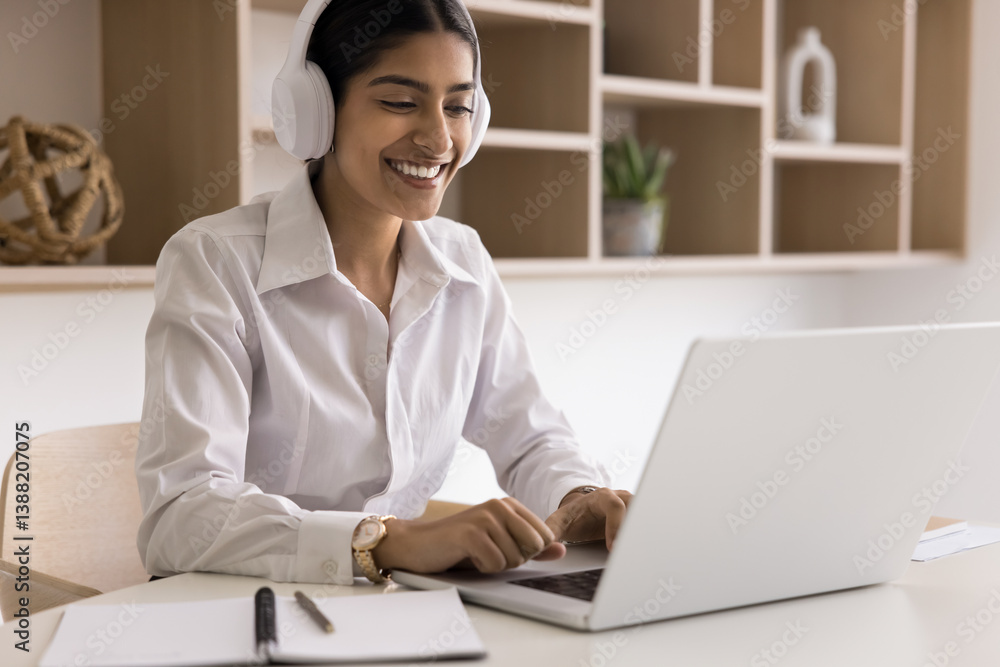 Smiling Indian woman in headphones look at laptop screen take part in on-line meeting by study or business, engaged in professional webinar in modern workspace. Video call, on-line lecture participant Smiling Indian woman in headphones look at laptop screen take part in on-line meeting by study or business, engaged in professional webinar in modern workspace. Video call, on-line lecture participant