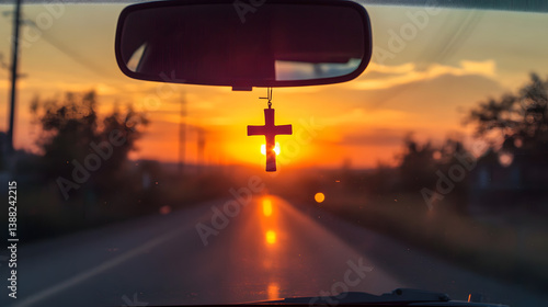 Driving into the sunset with faith. A cross hangs from the rearview mirror, reflecting the warm light. Travel, religion, and hope converge on the open road.