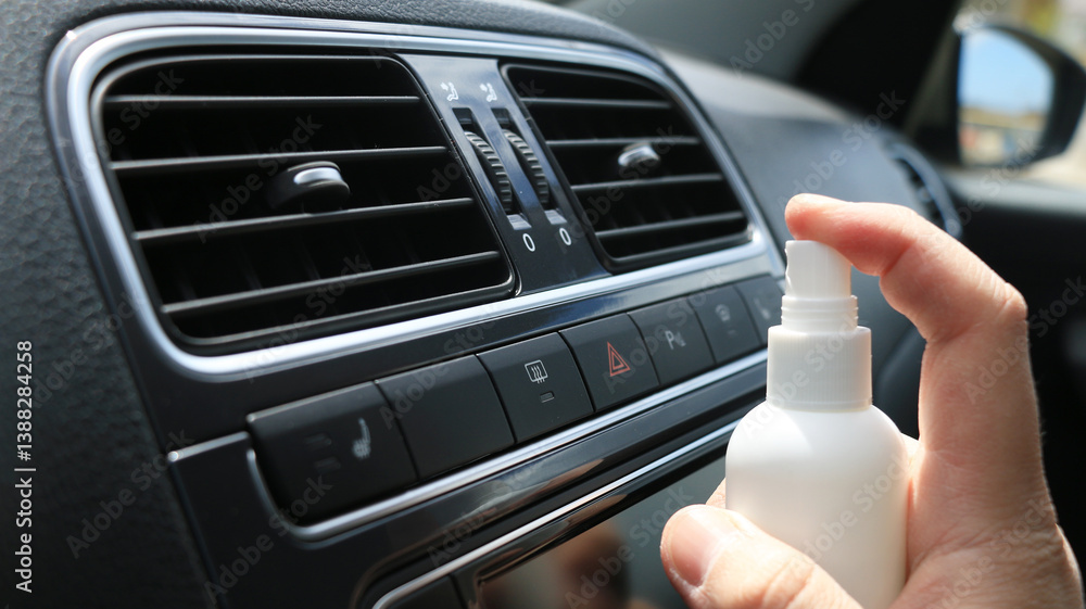 Obraz premium Hand spraying air freshener in car interior ventilation system