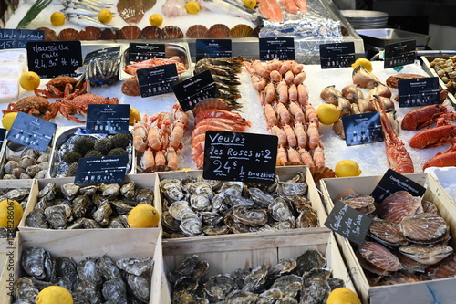 Fresh seafood market in France with oysters, shrimps, lemons, and price tags. Traditional French fish market with local shellfish and crustaceans on display.