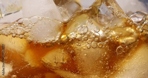 Pouring aromatic coffee onto ice cubes, closeup view through glass