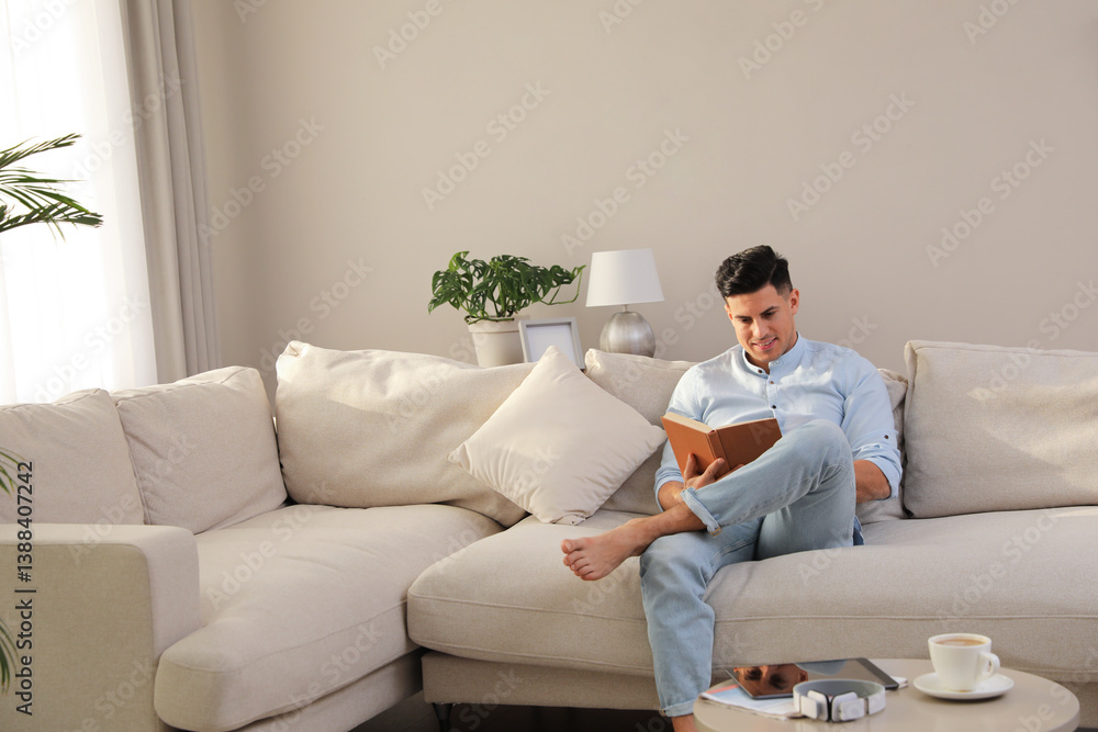 Man reading book on sofa in living room Man reading book on sofa in living room